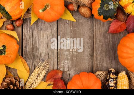 Telaio di autunno di foglie colorate e zucche oltre un rustico sfondo legno Foto Stock