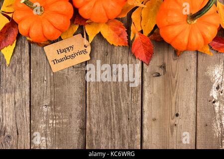 Felice regalo di ringraziamento tag con bordo superiore di zucche e foglie di autunno sul rustico sfondo legno Foto Stock