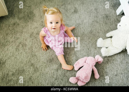 Ritratto di bambina (12-17 mesi) seduto sul pavimento Foto Stock