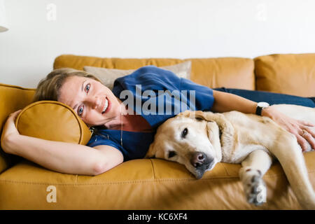 Donna e labrador retriever sdraiato sul divano Foto Stock