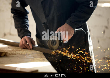 Artigiano lavora con utensile elettrico in officina Foto Stock