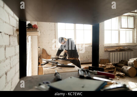Lavoratore manuale macinazione di metallo acciaio oggetti in officina con l'attrezzo Foto Stock