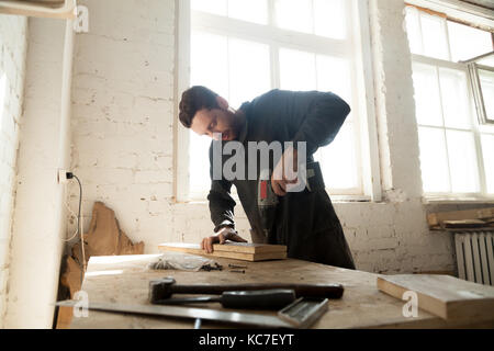 Giovane falegname facendo lavori in legno in falegnameria Foto Stock