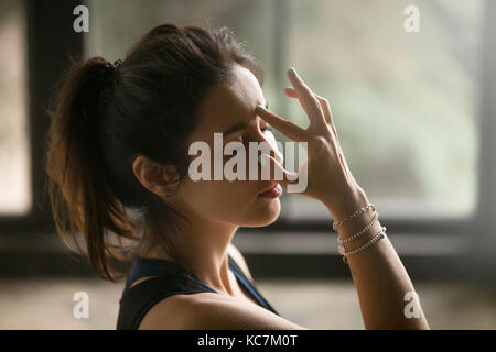 Giovane donna attraente nella narice alternativo di respirazione, studio ba Foto Stock