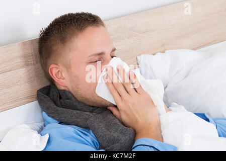 Ritratto di un giovane uomo con naso soffiando il suo naso Foto Stock