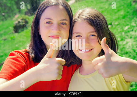 Ritratto di pretty teenage sorelle mostra Thumbs up. Escursioni nella natura. In stile retrò di colori Foto Stock