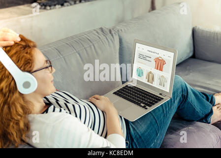 Rilassante donna incinta usando un computer portatile Foto Stock