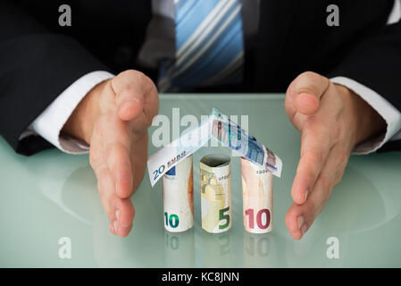 Close-up di un imprenditore proteggere casa fatta di banconote Foto Stock