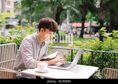 Giovane maschio lavoro freelance con computer portatile in confortevole coffee shop Foto Stock