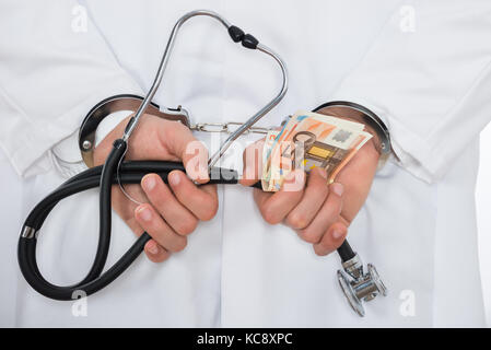 Close-up di medico con banconote in euro e manette Foto Stock