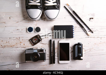 Scrivania con smartphone e forniture scolastiche. studio shot in bianco sullo sfondo di legno. Foto Stock