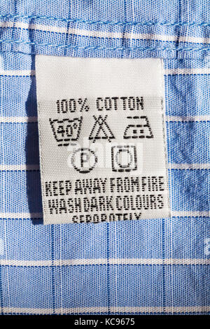 Cura i simboli di lavaggio e le istruzioni sull'etichetta in 100% cotone mans shirt - tenere lontano dal fuoco di lavare i colori scuri separatamente Foto Stock