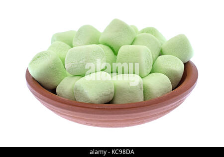 Una piccola rossa argilla ciotola riempita con miniaturizzate green marshmallows isolato su uno sfondo bianco. Foto Stock