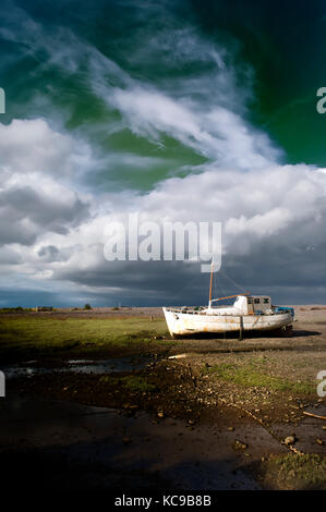 Vecchia barca da pesca sul fango a molto bassa marea sotto una drammatica e cielo tempestoso al crepuscolo in porlock weir, somerset, Regno Unito. solitario, spettrale, prenota-cover Foto Stock