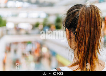 Giovane donna esplorare moderno centro commerciale Foto Stock