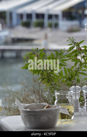 Un tavolo per la cena in una taverna greca o un ristorante nei pressi di un porto sull'isola greca di Corfù. Condimenti e acqua impostata su una tabella per la Diners. Foto Stock