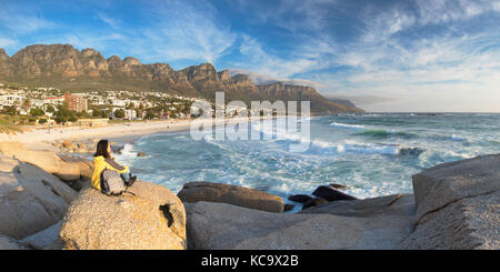 Donna seduta sulle rocce a Camps Bay, Città del Capo, Western Cape, Sud Africa (MR) Foto Stock