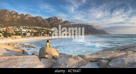 Donna seduta sulle rocce a Camps Bay, Città del Capo, Western Cape, Sud Africa (MR) Foto Stock