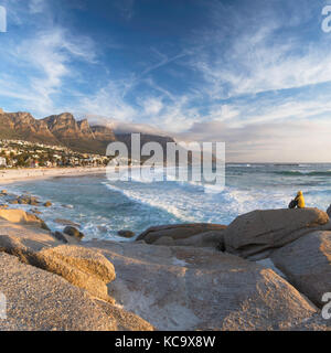 Donna seduta sulle rocce a Camps Bay, Città del Capo, Western Cape, Sud Africa (MR) Foto Stock