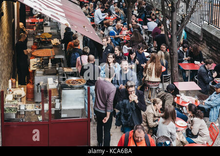 La gente camminare passato le bancarelle del mercato di Borough Market, uno dei più grandi e più antiche i mercati alimentari a Londra. Foto Stock