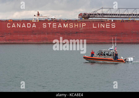 Sault Ste Marie, michigan - un u.s coast guard boat vicino al csl laurentien, grandi laghi carichi alla rinfusa freighter, sulla st. Mary river, appena al di sotto del th Foto Stock