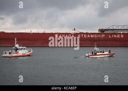 Sault Ste Marie, michigan - Stati Uniti coast guard barche vicino al csl laurentien, grandi laghi carichi alla rinfusa freighter, sulla st. Mary river, appena al di sotto della Foto Stock