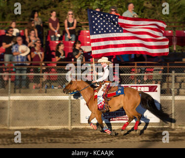 Rodeo regina equitazione con la bandiera americana al pro rodeo in enumclaw, wa Foto Stock