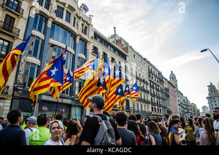 Diverse bandiere della Catalogna sono visto circondato da una grande folla che va al Plaza Universidad durante una manifestazione di protesta. Migliaia di persone che occupano le strade di Barcellona. Essi stanno protestando contro la polizia nazionale spagnola la violenta durante il referendum. Foto Stock