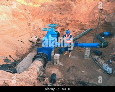 Città principale tubazione di alimentazione dell'acqua. Il personale tecnico del giubbotto metropolitana tubazione di comando gate. Riparato sistema di pipeline. Controllo finale di tubi Foto Stock