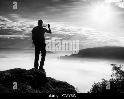 Uomo forte escursionista photogrphy con smart phone al picco di montagna. splendida alba. Foto Stock