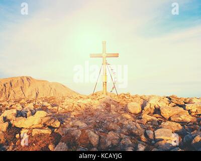 Grande croce sulla cima della montagna come tipico delle Alpi. croce di legno al picco di montagna con la preghiera buddista flags flutter in forte vento. Monumento a vi Foto Stock