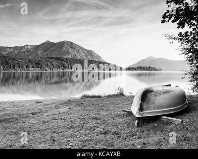 Sottosopra la pesca in barca a remi sulla banca del lago delle Alpi. mattina autunnale di lago. drammatica e pittoresca scena. montagne in specchio d'acqua. Foto Stock