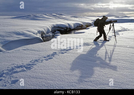 MODRUDALUR, ISLANDA, 2 marzo 2016 : UN fotografo lavora nel paesaggio innevato delle Highlands islandesi Foto Stock