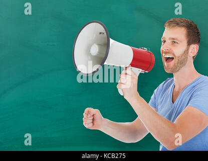 Giovane uomo felice facendo un annuncio sul megafono davanti di Blackboard Foto Stock