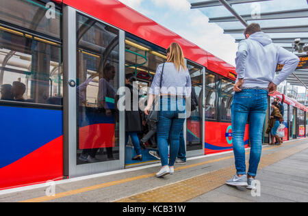 Passeggeri / pendolari di salire a bordo di un treno durante le ore diurne, alla Royal Victoria station sulla Docklands Light Railway (DLR) sistema, East London, England, Regno Unito. Foto Stock