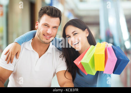 Ritratto di un giovane sorridente con un colorato borsa da shopping nel Centro Commerciale per lo Shopping Foto Stock