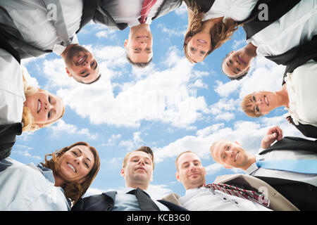 Ritratto di una società multietnica imprenditori formando Huddle contro Sky Foto Stock