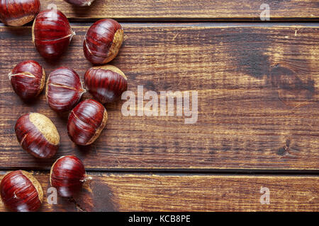 Vista dall'alto di castagne sulla scrivania di legno formando bordo sinistro per spazio di copia Foto Stock