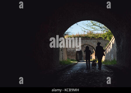 Madre e figlia camminando in un tunnel con un cane Foto Stock