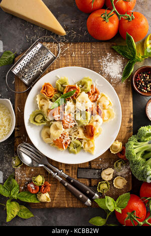 Rosso, bianco e verde di tortellini con verdure e formaggio Foto Stock