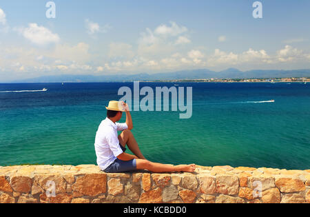 L'uomo gode di vista sul mare in località estiva in una giornata di sole. giovane uomo di relax presso il mare mediterrinean. Foto Stock