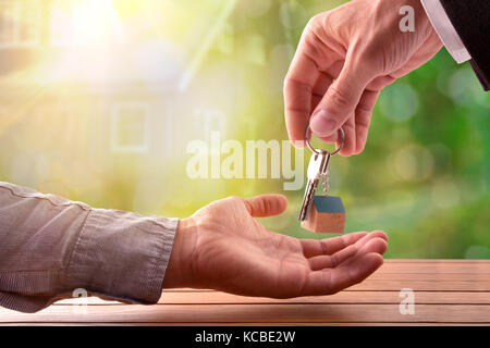 Agente di dare le chiavi per il compratore di una casa con casa su sfondo natura Foto Stock