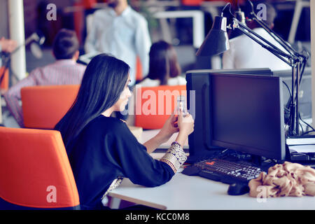 Ritratto di giovane annoiato donna attraente alla scrivania in ufficio, con il computer portatile, cercando un po' di buona musica Foto Stock