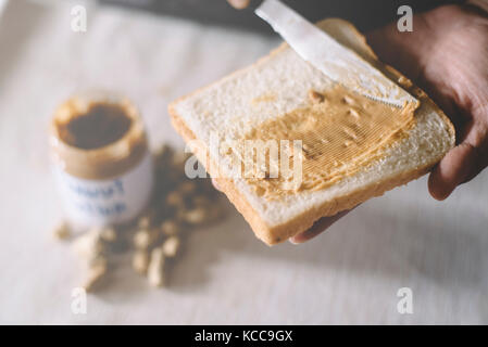 Diffusione di burro di arachidi sul pane Foto Stock
