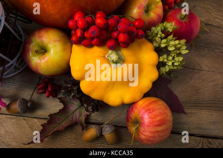 Concetto di raccolto con zucca gialla vegetale, rowan bacche, mele e ghiande. Foto Stock