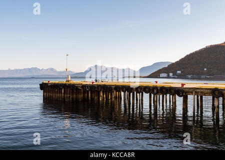 Pier rivestita con pneumatici come i parafanghi per le barche, sul mare e sulle montagne sullo sfondo, harstad in Norvegia Foto Stock