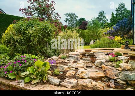 Un nuovo impianto di rock garden dopo aver installato una mano-costruita in pietra naturale cascata in un giardino inglese nel Regno Unito Foto Stock