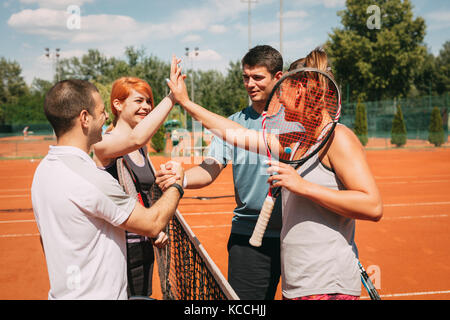 Quattro giovani amici dando una alta cinque dopo corsi di tennis. messa a fuoco selettiva. Foto Stock