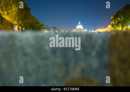 (Fuoco selettivo) Tenebrologo della Basilica di San Pietro. Foto scattata sulle rive del fiume Tevere con il terreno in primo piano Foto Stock