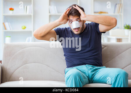 Giovane uomo recuperando la guarigione a casa dopo un intervento di chirurgia plastica naso job Foto Stock